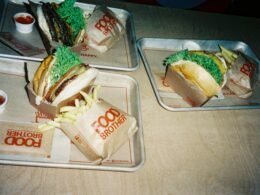 Zwei Tabletts mit verschiedenen Speisen stehen nebeneinander auf einem Holztisch in gemütlicher Atmosphäre.