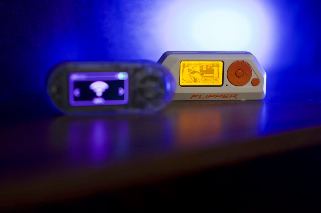 Zwei tragbare elektronische Geräte liegen nebeneinander auf einer glänzenden, reflektierenden Oberfläche.