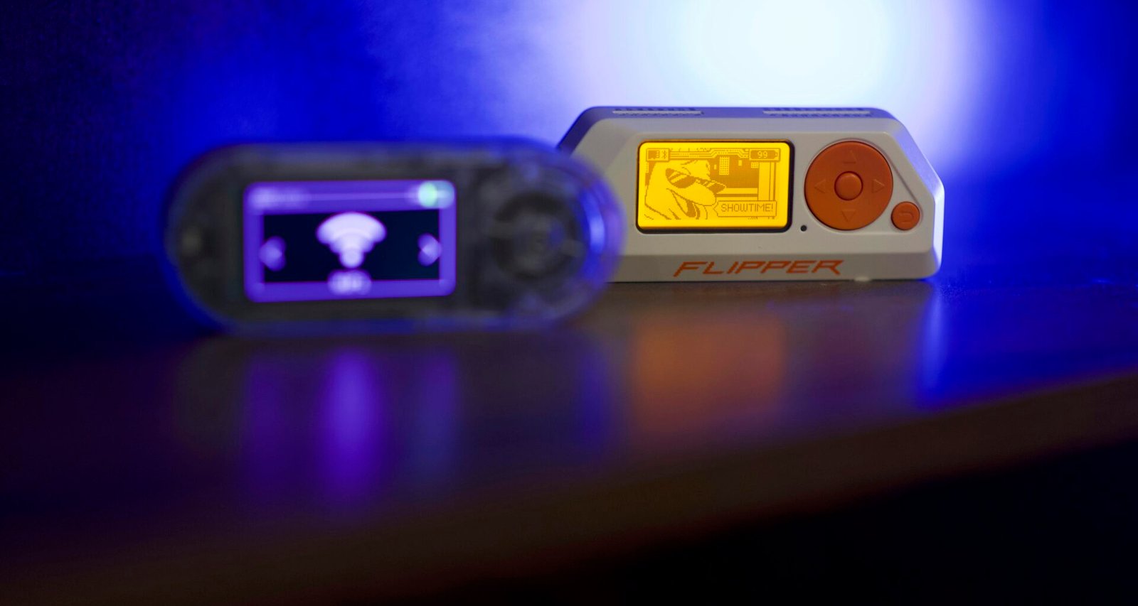 Zwei tragbare elektronische Geräte liegen nebeneinander auf einer glänzenden, reflektierenden Oberfläche.