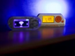 Zwei tragbare elektronische Geräte liegen nebeneinander auf einer glänzenden, reflektierenden Oberfläche.