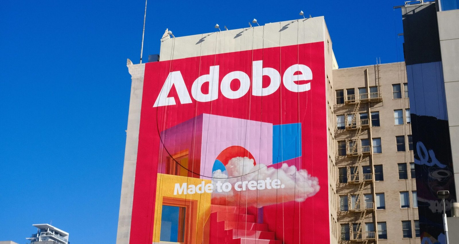 Adobe Logo und Slogan deutlich sichtbar an der Außenfassade eines Geschäftsgebäudes aufgenommen