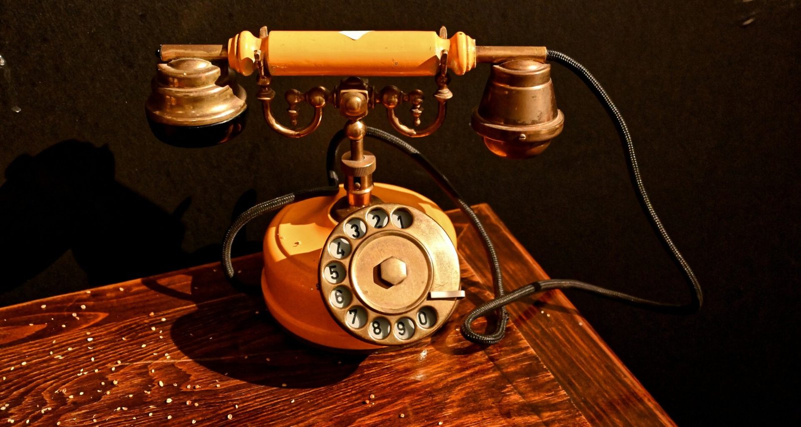 Antikes schwarzes Wählscheibentelefon steht auf einem Holztisch, aufgenommen aus der Nähe, Umgebung unscharf