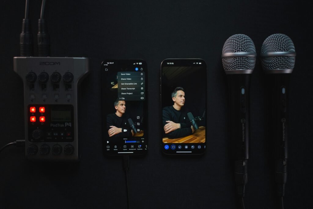 Audio Recorder, Smartphones und Mikrofone liegen nebeneinander auf einer dunklen Oberfläche als Arrangement für Tonaufnahmen.