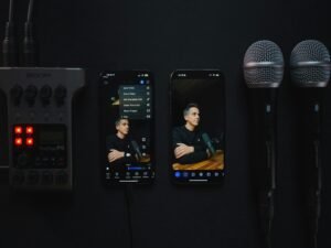 Audio Recorder, Mobiltelefone und Mikrofone arrangiert auf einem dunklen Tisch. Fokus auf moderne Audiotechnik.