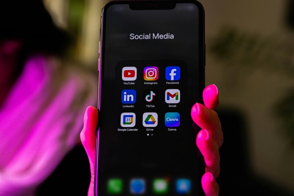 Ein Smartphone, auf dessen Bildschirm verschiedene Social Media App-Symbole abgebildet sind, liegt auf einer Oberfläche.