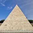 Eine beige Pyramide bei Tageslicht, geometrische Architektur aus Stein mit klaren Linien, freistehend im Außenbereich