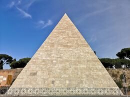 Eine beige Pyramide bei Tageslicht, geometrische Architektur aus Stein mit klaren Linien, freistehend im Außenbereich