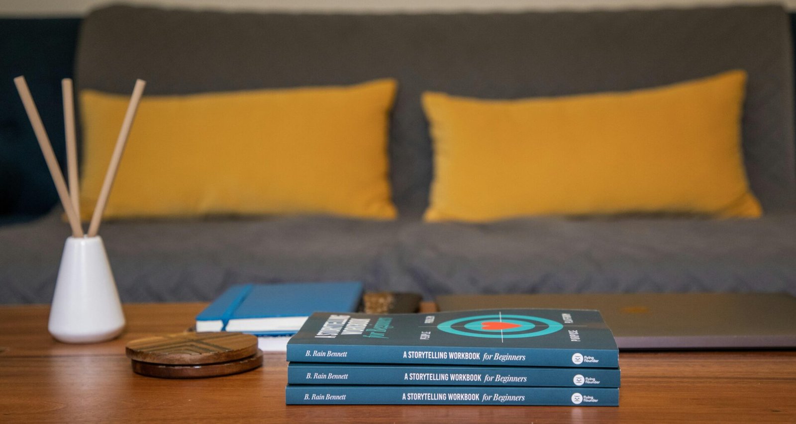 Ein blaues und gelbes Buch liegt auf einem braunen Holztisch, aufgenommen aus der Vogelperspektive.