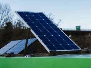 Blau-weißes Solarpanel installiert auf grünem Metallbalken bei Tageslicht, Symbol für nachhaltige Energiegewinnung