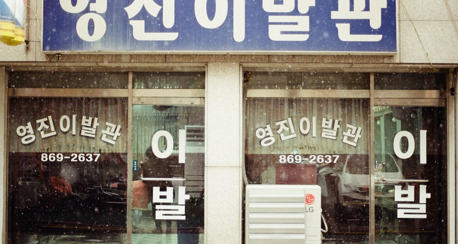 Braunes und weißes Geschäft aus Holz mit großen Fenstern, aufgenommen aus der Straßenperspektive