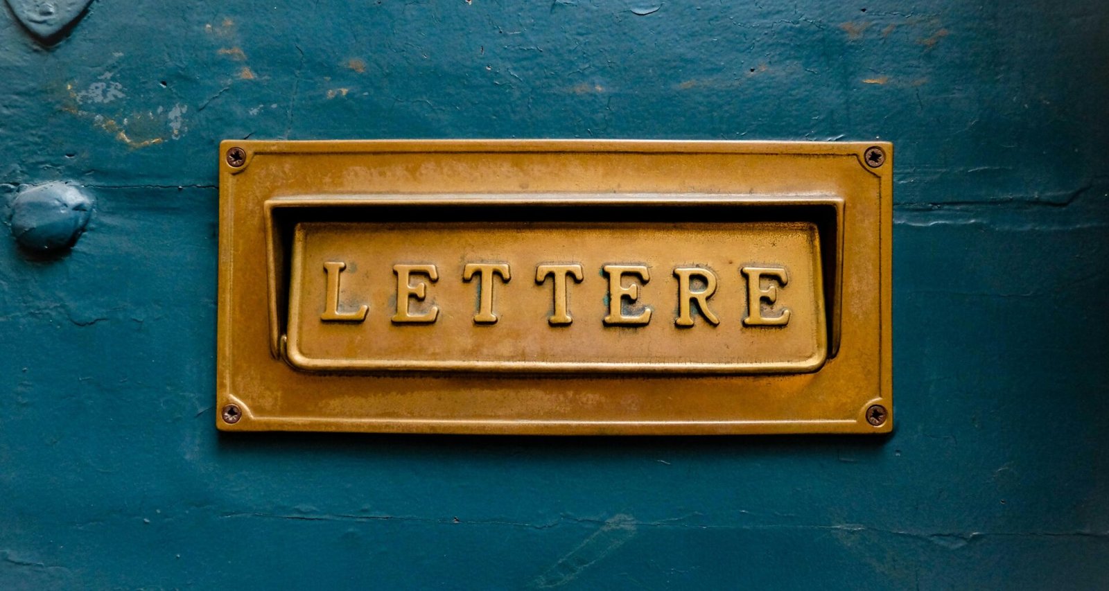 Braune Buchstaben einer Beschilderung auf einer türkisfarbenen Wand mit klarem, kontrastreichem Design.