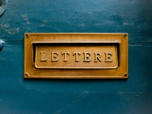 Braune Leuchtschrift mit dem Wort 'Lettere' auf einer glatten, türkisfarbenen Wand als kreatives Fassadenelement