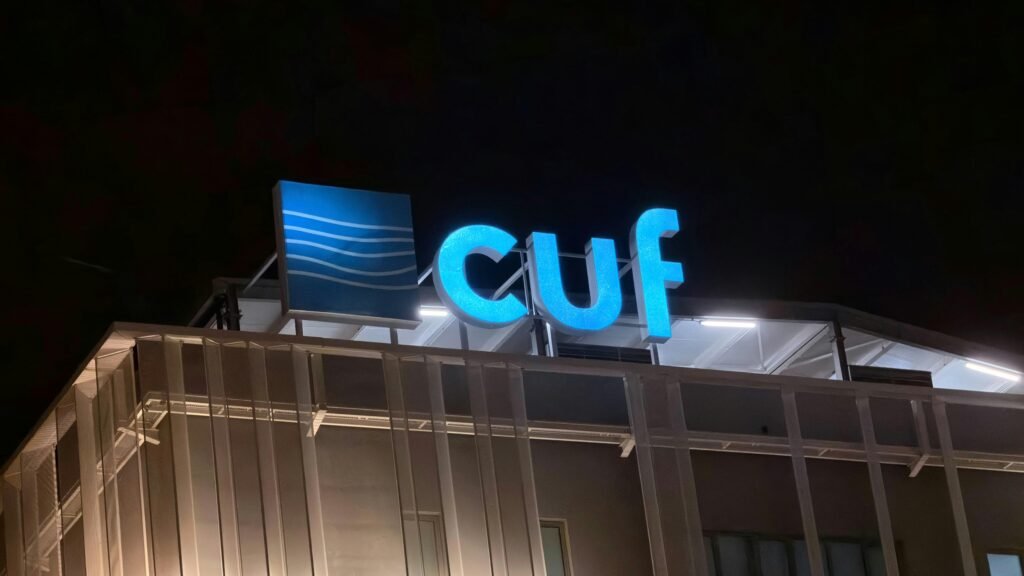 Beleuchtetes Cuf Logo bei Nacht an der Fassade eines Gebäudes, modernes Stadtambiente