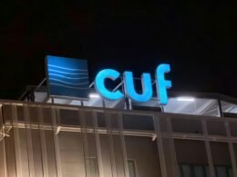 Beleuchtetes Cuf Logo bei Nacht an der Fassade eines Gebäudes, modernes Stadtambiente