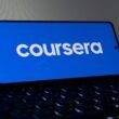Das Coursera-Logo ist deutlich auf dem Bildschirm eines Smartphones zu sehen, fotografiert aus der Nähe für einen klaren Fokus.