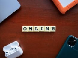 Scrabble-Buchstaben, die das Wort Online auf einem hölzernen Tisch bilden. Symbol für digitale Präsenz und Online-Themen.