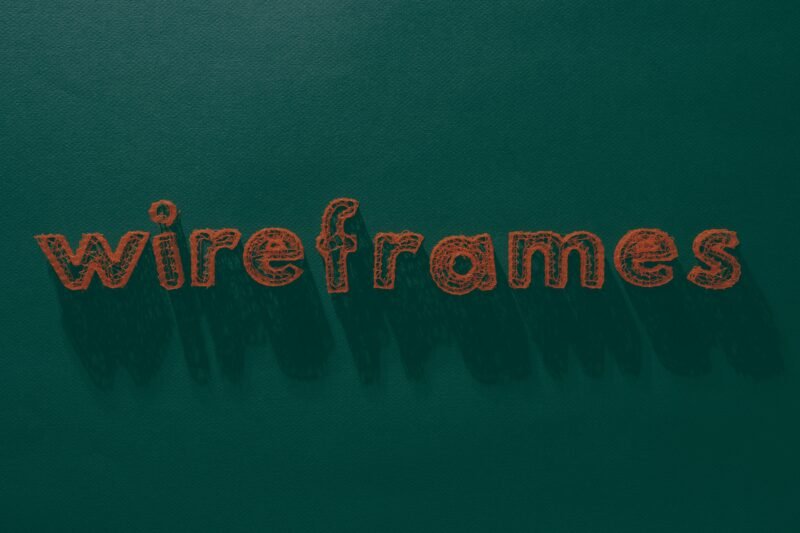 Das Wort 'Wireframes' steht weiß geschrieben auf einer grünen, strukturierten Oberfläche – Symbol für Webdesign-Prozesse.