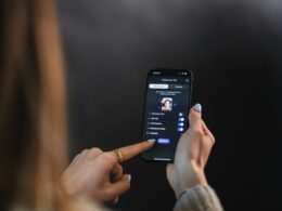 Nahaufnahme einer weiblichen Hand, die das Display eines modernen Smartphones berührt und bedient.