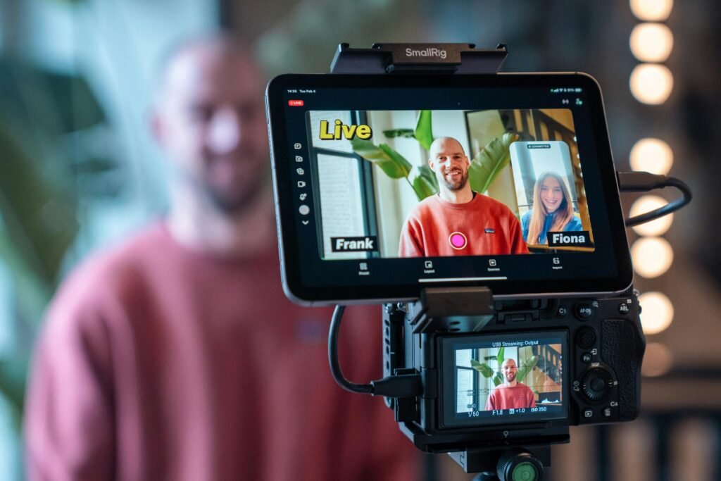 Kamera filmt einen Live-Videoanruf mit zwei Personen auf einem Bildschirm in einem modernen Arbeitsumfeld.