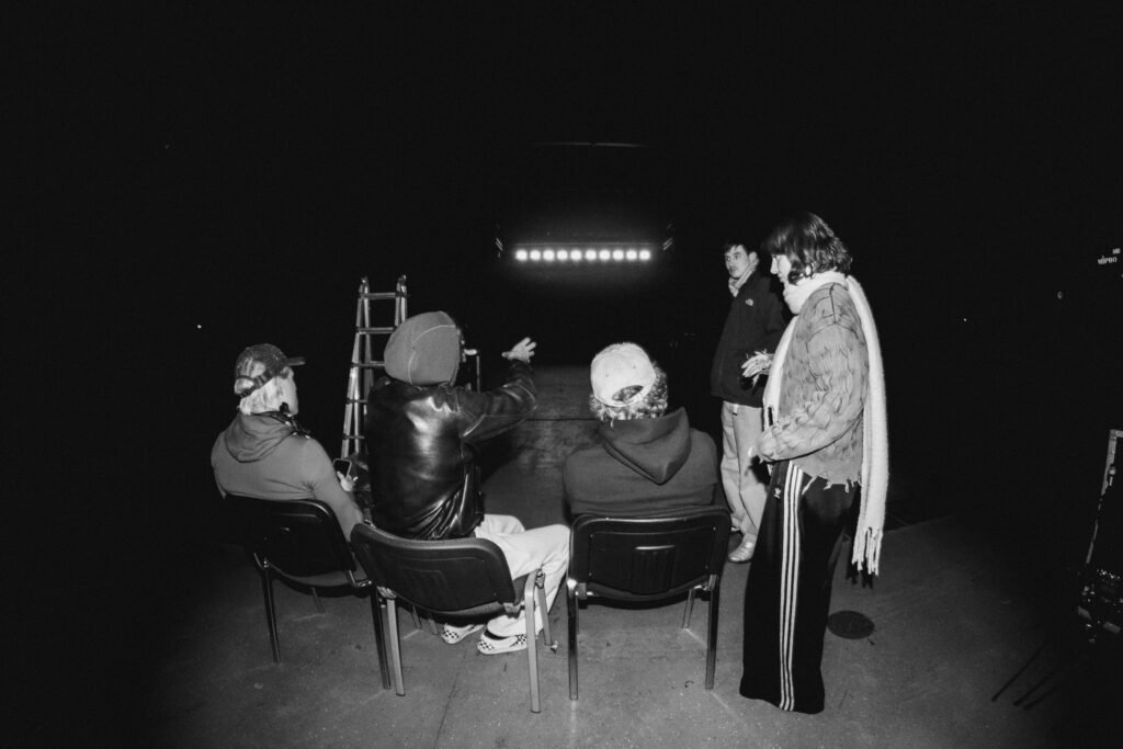 Mehrere Personen sitzen in einem dunklen Raum und schauen aufmerksam auf einen großen beleuchteten Bildschirm.