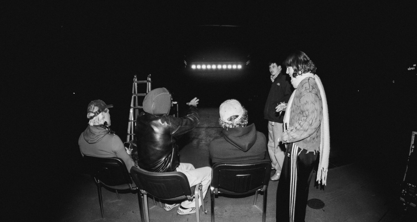 Mehrere Personen sitzen in einem dunklen Raum und schauen aufmerksam auf einen großen beleuchteten Bildschirm.