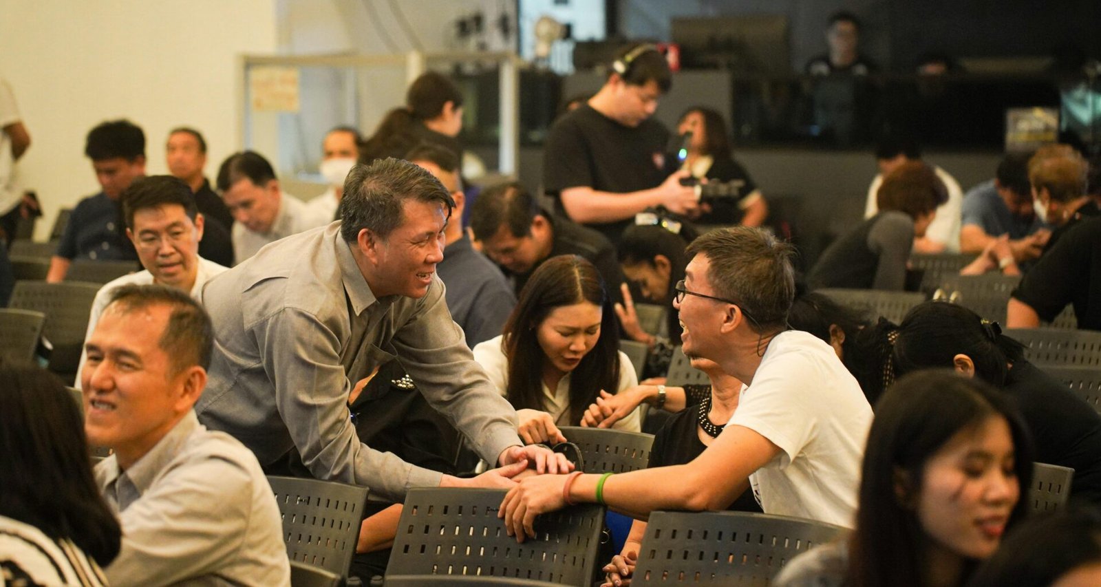 Mehrere Menschen in einem modernen Raum, einige führen Unterhaltungen und tauschen sich aus, andere stehen zusammen.