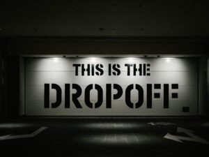 Im Dunkeln leuchtendes Dropoff-Schild auf einem Parkplatz, aufgenommen aus der Nähe, mit Fokus auf die Beschriftung