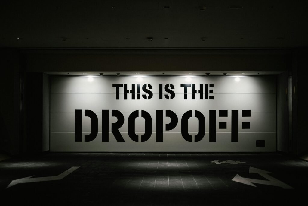 Beleuchtetes Dropoff-Schild in der Nacht vor dunklem Hintergrund, fotografiert von tommao wang