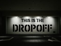 Beleuchtetes Dropoff-Schild in der Nacht vor dunklem Hintergrund, fotografiert von tommao wang