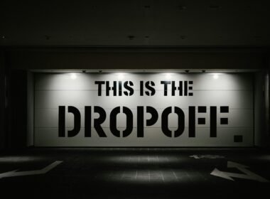 Beleuchtetes Dropoff-Schild in der Nacht vor dunklem Hintergrund, fotografiert von tommao wang