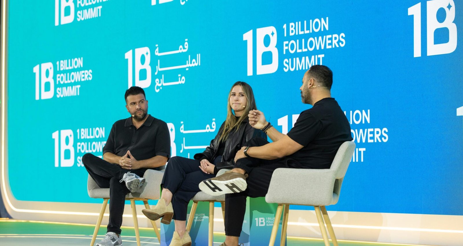 Drei Menschen sitzen auf einer Bühne in einer Paneldiskussion und tauschen sich über digitale Themen aus