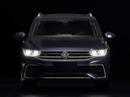 Dunkelblauer Volkswagen SUV mit leuchtenden Frontscheinwerfern auf Straße bei Dämmerung, moderner Look