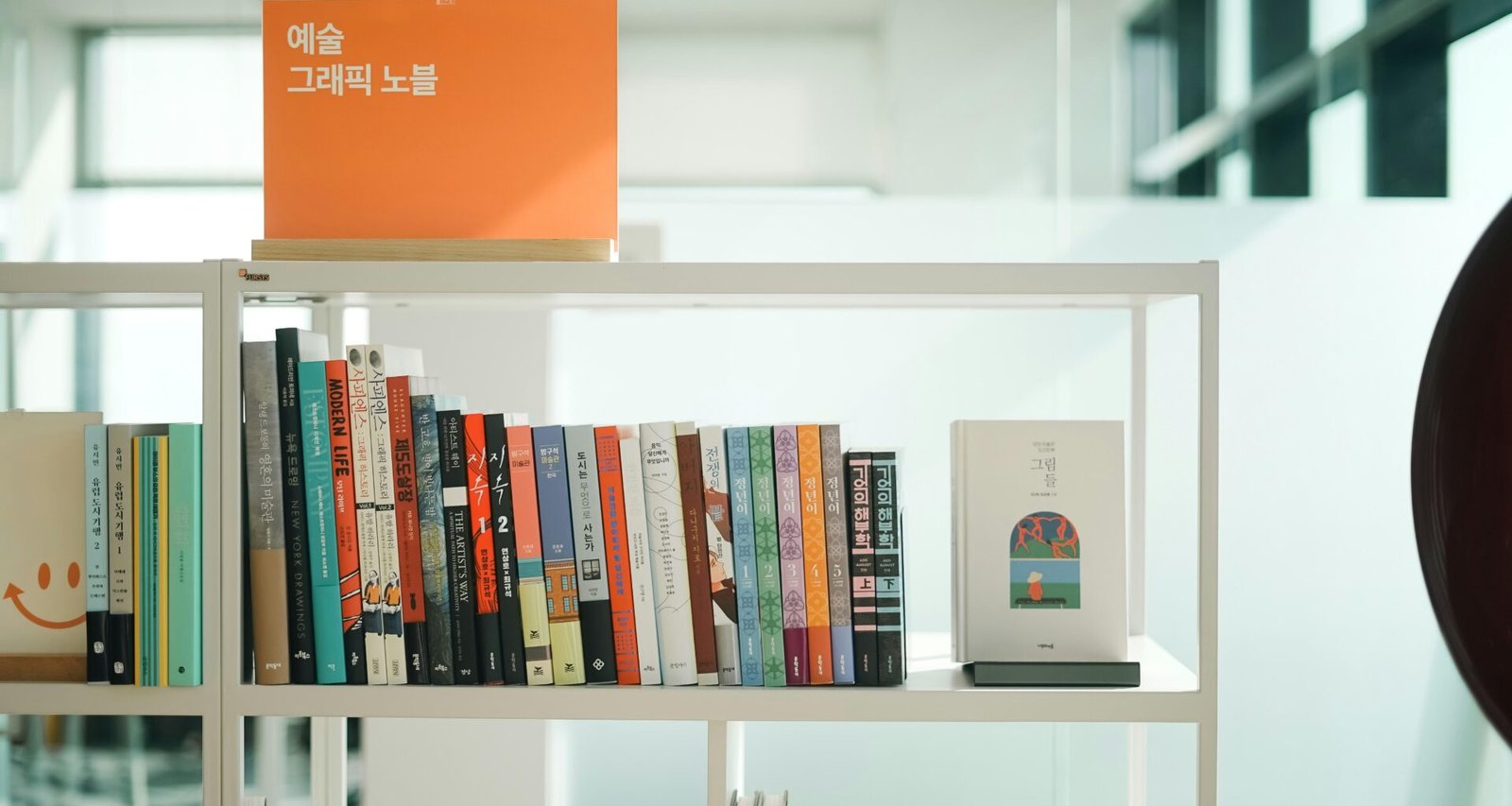 Ein Bücherregal voller Bücher steht neben einer klassischen Wanduhr und bietet einen geordneten Anblick im Raum.