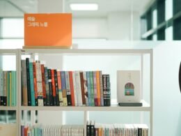 Ein Bücherregal voller Bücher steht neben einer klassischen Wanduhr und bietet einen geordneten Anblick im Raum.