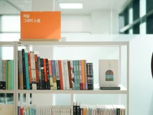 Ein Bücherregal voller Bücher steht neben einer klassischen Wanduhr und bietet einen geordneten Anblick im Raum.