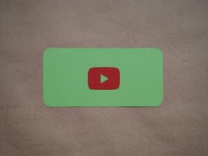 Grünes Rechteck mit rotem Play-Button als Symbol für digitale Medien und Videoinhalte auf neutralem Hintergrund