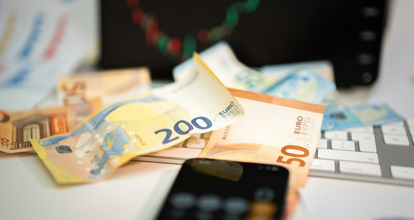 Ein Mobiltelefon liegt auf einem Stapel von Geldscheinen – verdeutlicht die Verbindung zwischen Technologie und Finanzen.