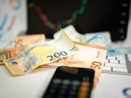 Ein Mobiltelefon liegt auf einem Stapel von Geldscheinen – verdeutlicht die Verbindung zwischen Technologie und Finanzen.