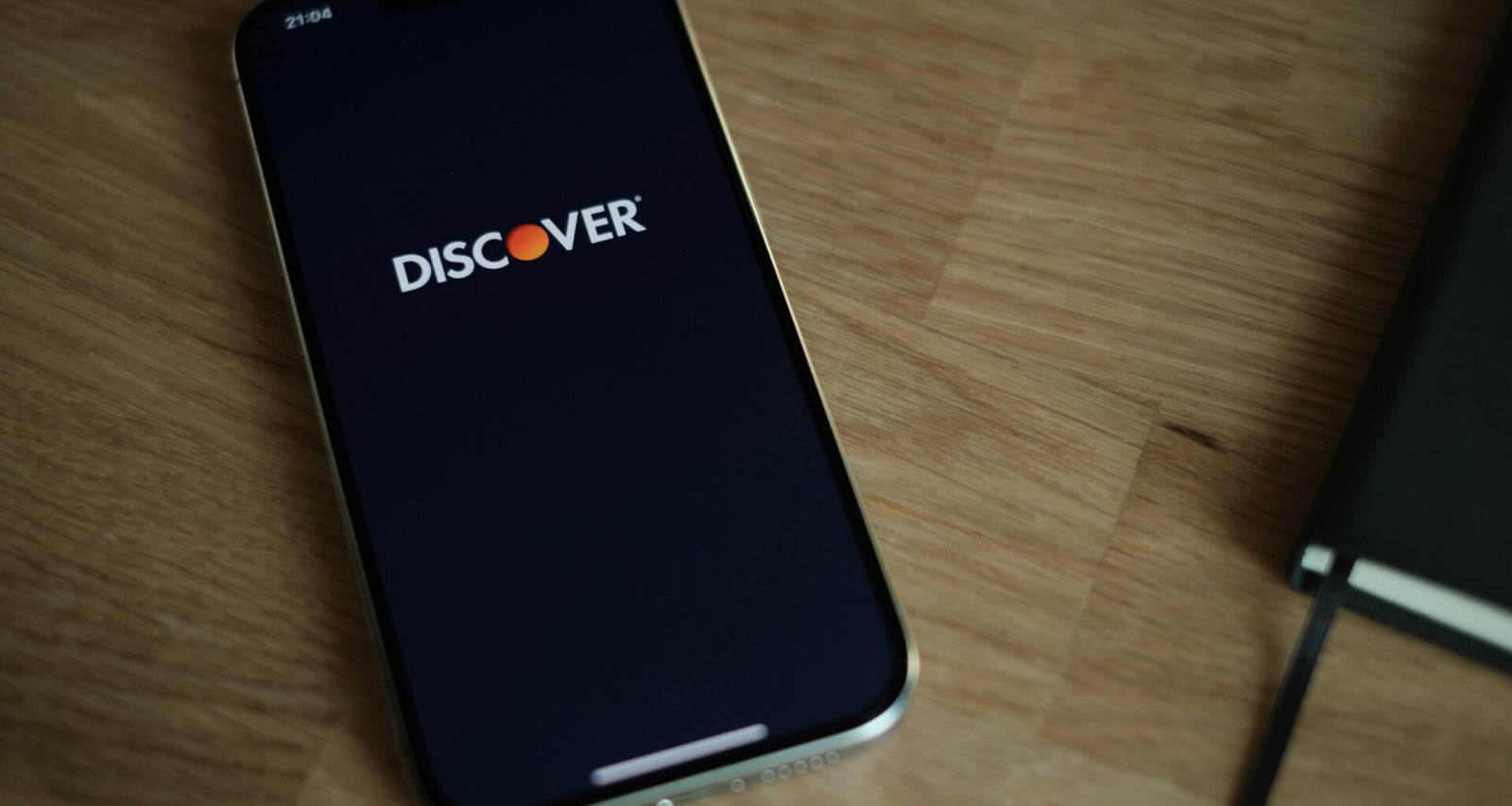 Ein Smartphone liegt auf einem hölzernen Tisch. Klare Sicht auf das Gerät und die Maserung des Holzes im Hintergrund.