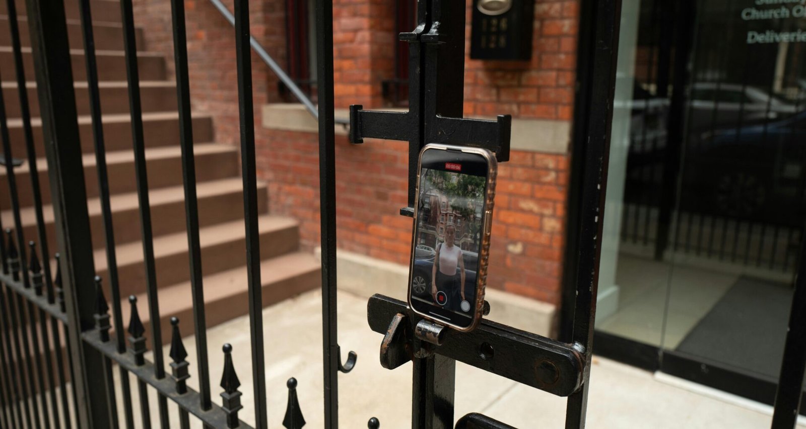 Ein Smartphone, das mit einer Halterung an einem Maschendrahtzaun befestigt ist, draußen aufgenommen