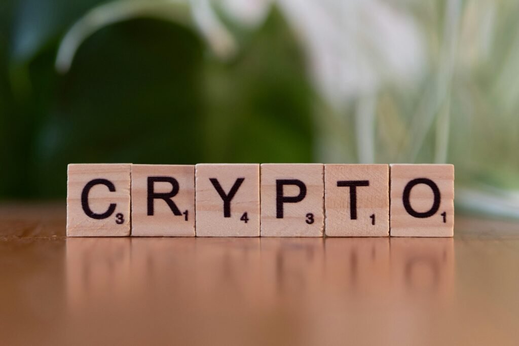 Ein Holzblock mit dem Schriftzug ‚Crypt‘ liegt auf einem Tisch, als Verweis auf Kryptowährungen und digitale Finanzthemen.