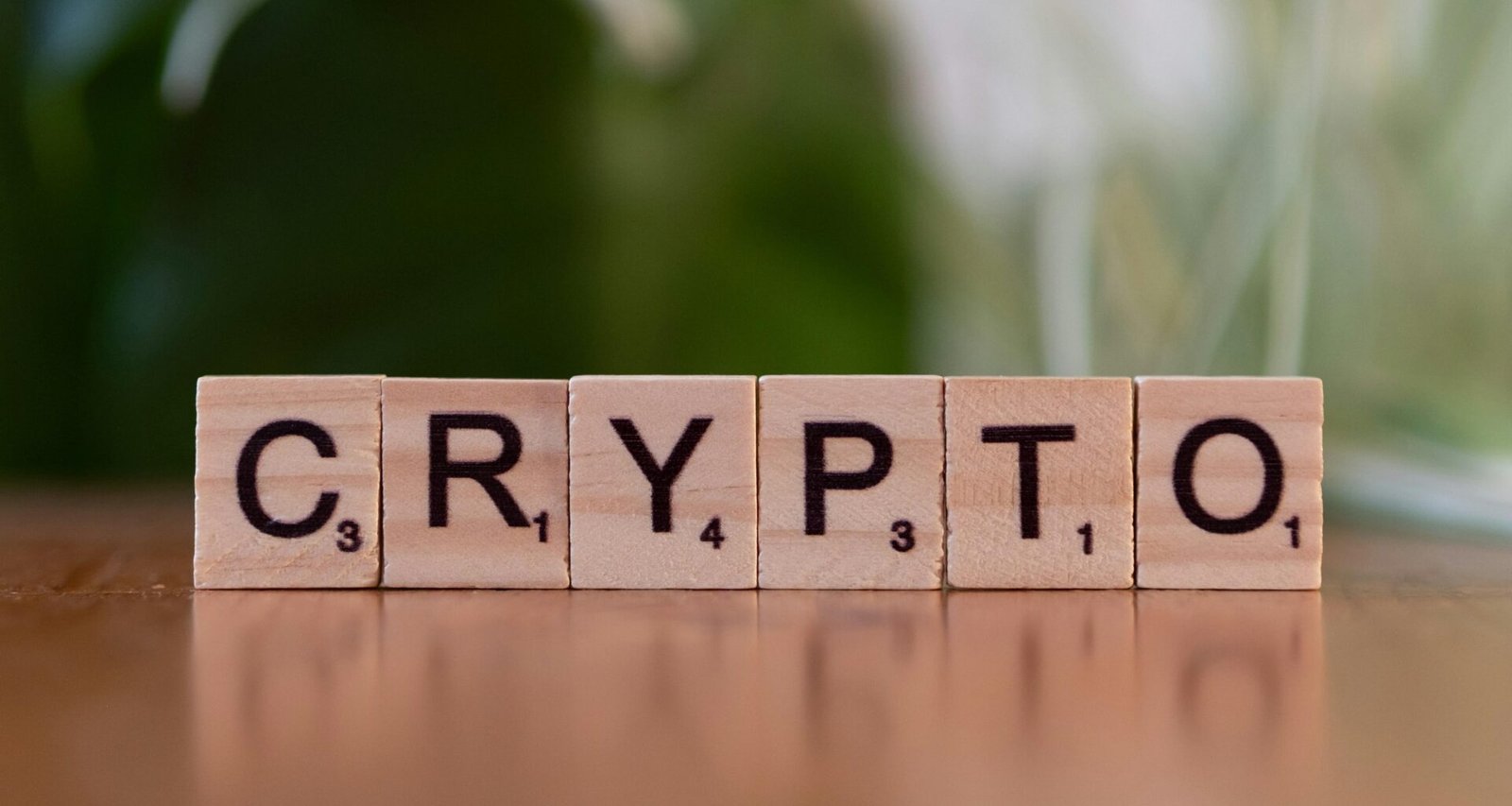 Ein Holzblock mit dem Schriftzug ‚Crypt‘ liegt auf einem Tisch, als Verweis auf Kryptowährungen und digitale Finanzthemen.