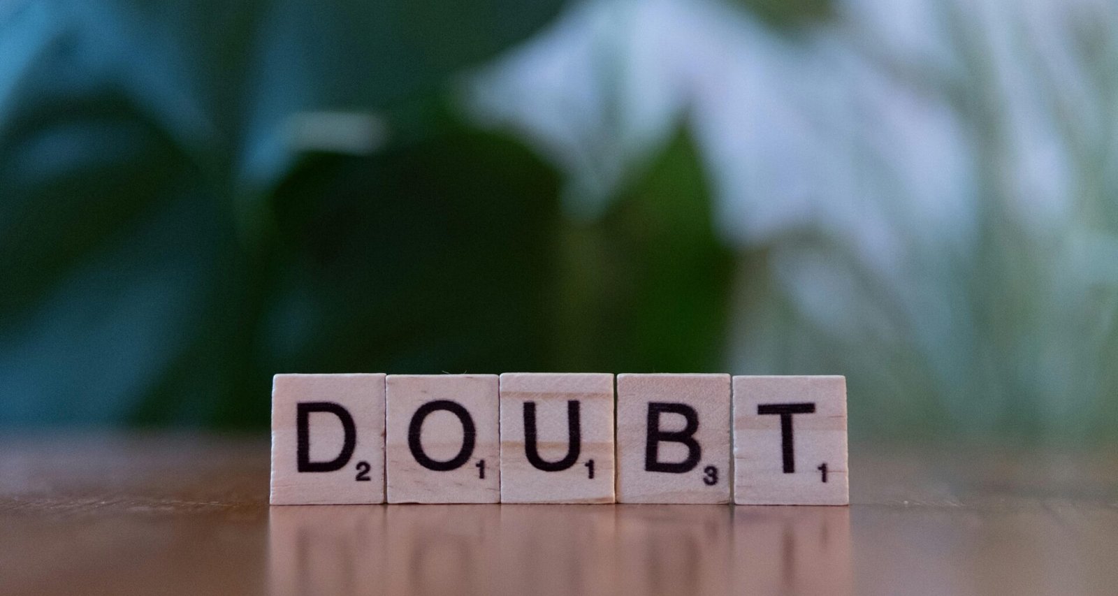 Ein Holzwürfel mit der Aufschrift doubt liegt auf einem Tisch und illustriert das Thema Unsicherheit im Berufsalltag.
