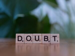 Ein Holzwürfel mit der Aufschrift doubt liegt auf einem Tisch und illustriert das Thema Unsicherheit im Berufsalltag.