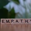 Ein Holzblock mit dem Schriftzug Empathie liegt auf einem Tisch; Fokus auf Begriff und Holzstruktur