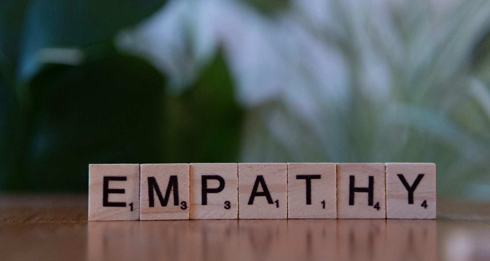 Ein Holzblock mit dem Schriftzug Empathie liegt auf einem Tisch; Fokus auf Begriff und Holzstruktur
