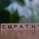 Ein Holzblock mit dem Schriftzug Empathie liegt auf einem Tisch; Fokus auf Begriff und Holzstruktur