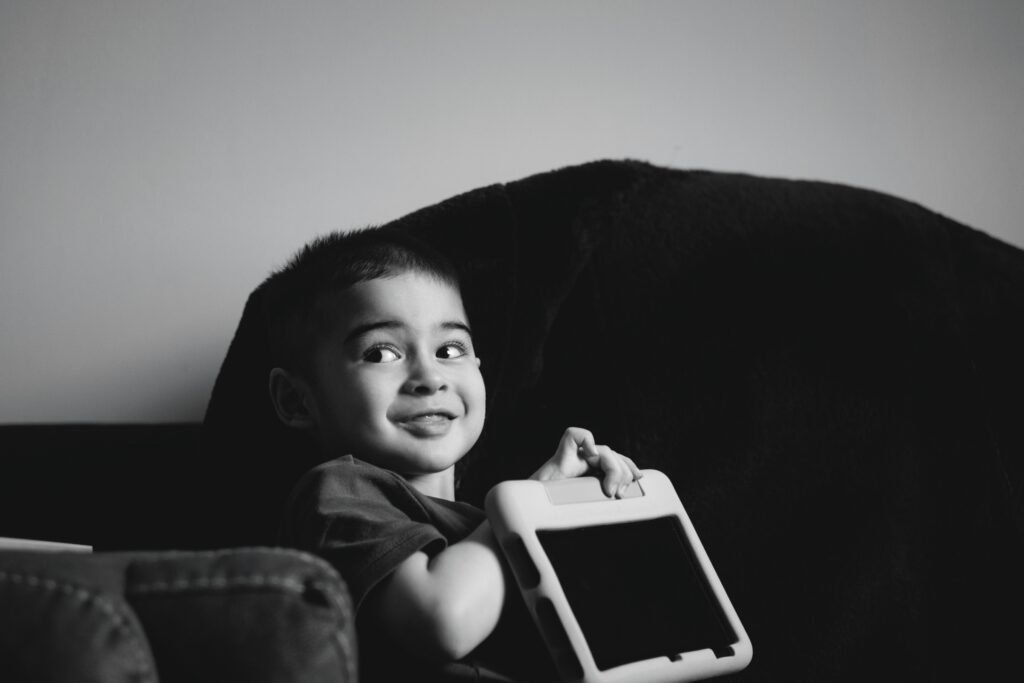 Junger Junge hält lächelnd ein Tablet in den Händen und schaut auf das Display, Symbol für digitale Bildung.