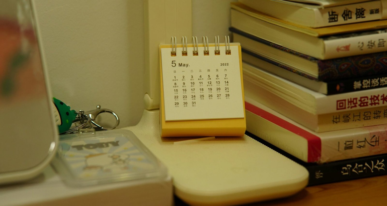 Ein kleiner Tischkalender steht neben einem Stapel Bücher auf einem Schreibtisch, ideal zur Veranschaulichung von Zeitmanagement.