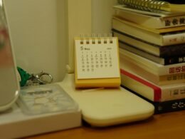 Ein kleiner Tischkalender steht neben einem Stapel Bücher auf einem Schreibtisch, ideal zur Veranschaulichung von Zeitmanagement.